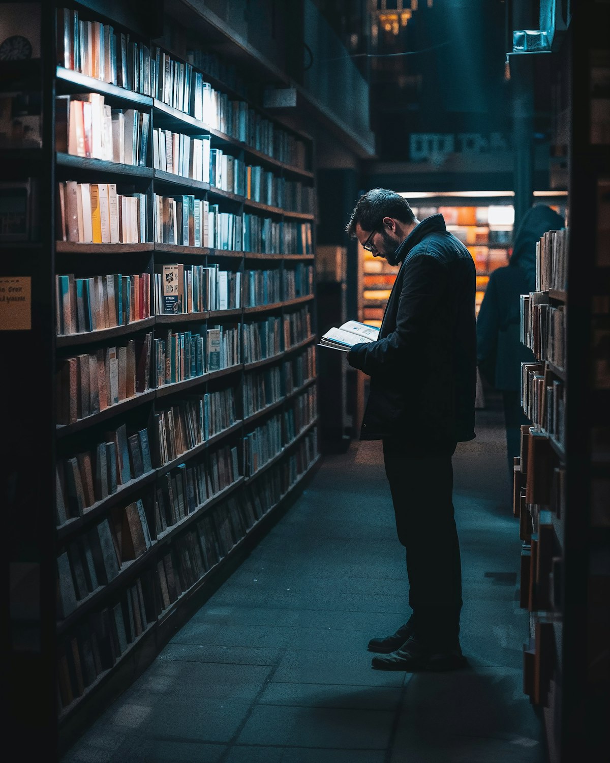 A person comfortably reading an e-reader in a dimly lit environment, showcasing the benefit of adjustable front lighting.