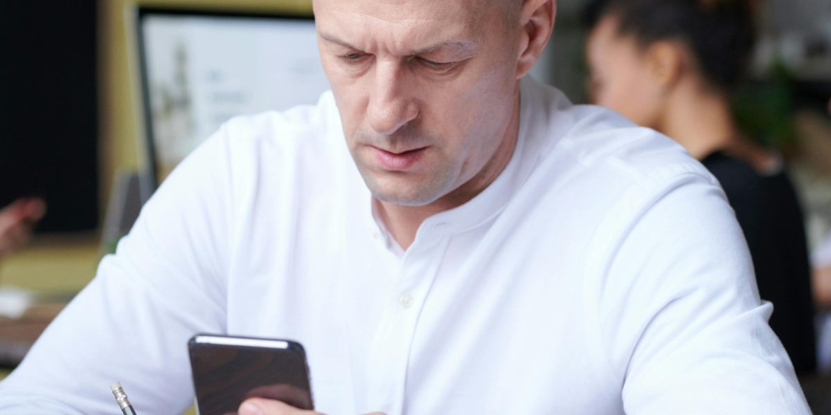 A person pausing with a thoughtful expression before interacting with their phone, practicing intentional habits.