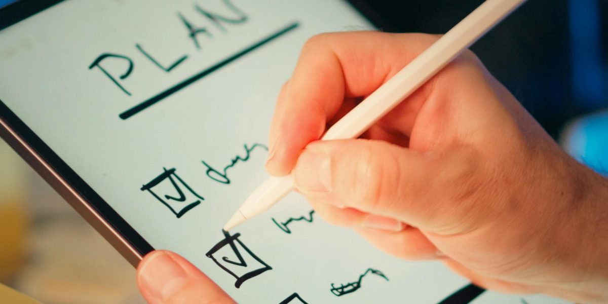 A person actively engaging with their study material by taking notes with a stylus, reinforcing learning.