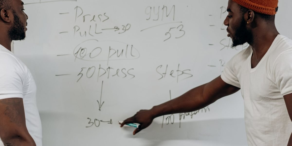 A person actively writing on a whiteboard, symbolizing the act of planning and establishing routines to maintain focus.
