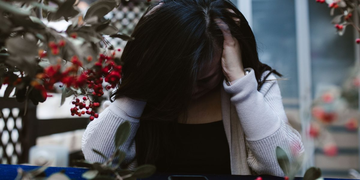 A person looking stressed, surrounded by digital notifications and multiple open screens, symbolizing modern work distractions.