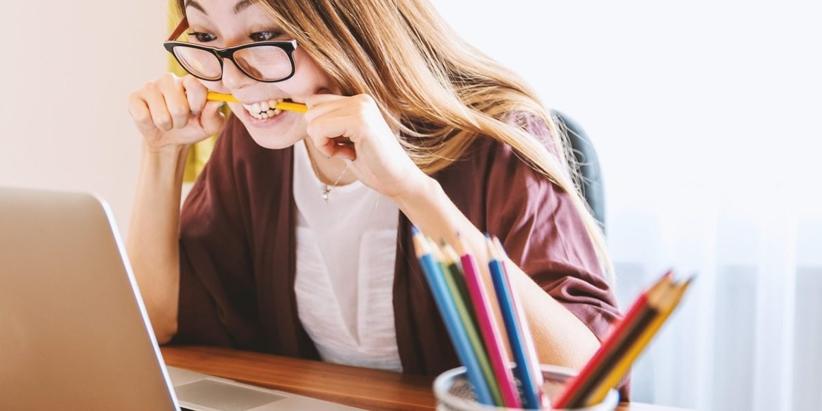 An individual looking stressed or frustrated while working at a desk, surrounded by potential digital distractions.
